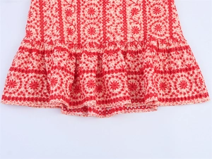 Detail of red and white floral embroidery and eyelet lace on layered ruffle dress hem