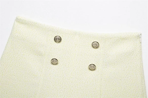 Dettaglio della gonna in tweed con bottoni metallici vintage e cerniera invisibile