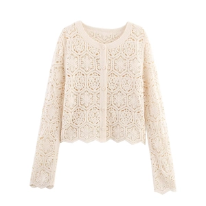 Detailed macro view of cream crochet floral pattern and scalloped hem on long sleeve top