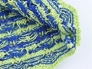 Macro shot of blue and neon green hollow-out knit fabric with detailed crochet texture