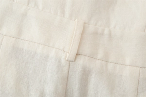 Detailed macro view of the cream cotton-linen fabric texture and belt loop stitching