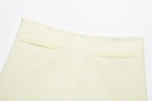 Dettaglio degli shorts in tweed giallo con tasche a filo e trama del tessuto rifinita