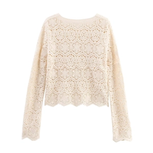 Detail of crochet floral hollow pattern on a long-sleeve cream top with scalloped cuffs
