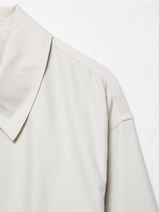 Close-up detail of the minimalist beige bomber jacket collar and shoulder stitching
