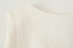 Detailed close-up of the linen fabric texture and neckline of the cream white vest