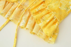 Détail macro du tissu floral jaune gaufré avec bords volantés et cordons de serrage