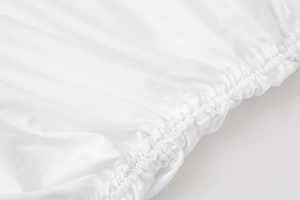 Close-up of white dress showing elastic cuff detail and textured stretchy fabric