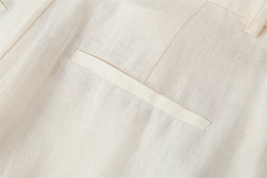 Detailed close-up showing the natural linen fabric texture and buttoned back pocket seam