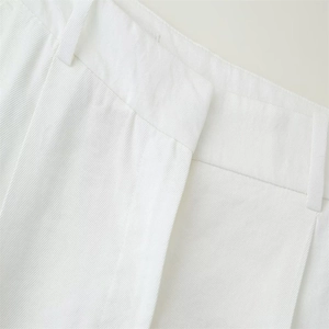 Close-up of white twill fabric texture and waistline tailoring on casual trousers