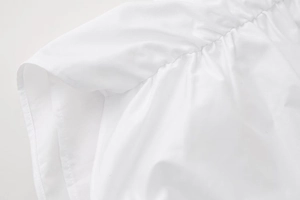 Detailed macro view of white woven fabric showing precise pleated stitching and twill texture