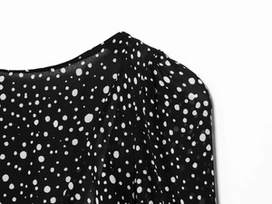 Close-up of neckline and puff sleeve details on a black polka dot chiffon dress
