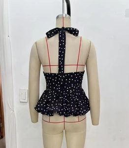 Detail of backless halter neck top with black and white polka dots and peplum hem