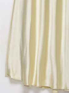 Dettaglio dell'abito in raso giallo chiaro con consistenza setosa e drappeggio elegante