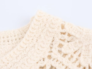 Macro shot of off-white long sleeve crochet lace top showing detailed knit patterns