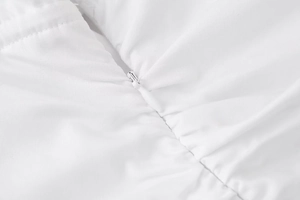 Detailed macro view of the invisible zipper design on a white minimalist dress fabric