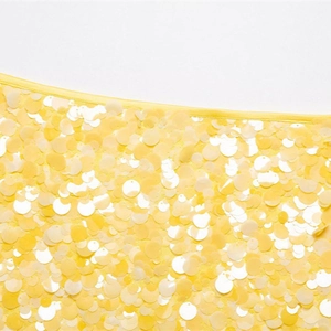 Primo piano del tessuto del mini abito con paillettes gialle e bordo rifinito a mano