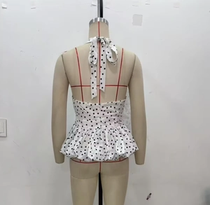 Detail of polka dot peplum top featuring halter neck straps and a hidden back zipper