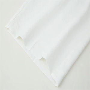 Detail of white cotton pants showing high-quality twill fabric and raw edge fringe hem