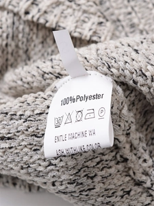 Detail shot of the 100% polyester fabric care label and S size tag on a knit dress
