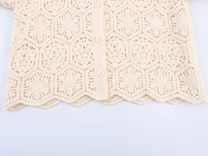 Close-up of beige crochet cardigan featuring hollow floral patterns and round buttons