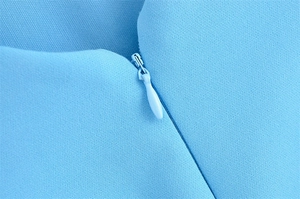 Detailed close-up of light blue fabric texture and hidden zipper on the wavy wide hem dress