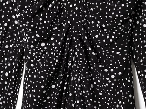 Detail of black and white polka dot chiffon dress featuring elegant ruched pleats and texture