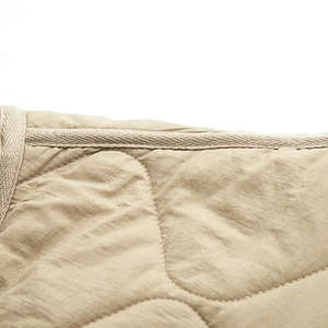 Macro close-up of beige quilted cotton fabric texture and neat braided edge piping