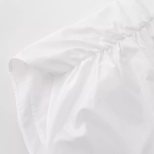Close-up of minimalist white slip dress featuring elegant shirring and a satin sheen finish