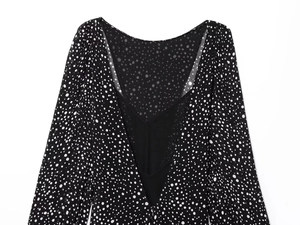Detail of V-neckline on black polka dot dress with long sleeves and matte finish fabric