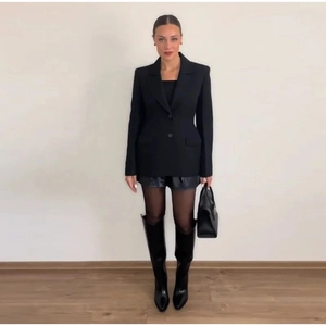 Detail of a slim-fit double-breasted knit blazer with padded shoulders in an all-black look