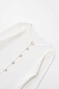 Detail of white ribbed knit cardigan with unique silver metallic buttons and crew neck
