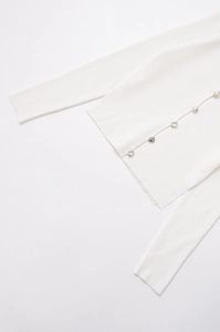 Close-up of white ribbed knit cardigan with unique irregular silver lava metal buttons