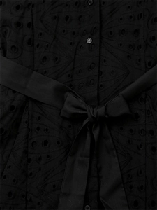 Détail d'une robe noire en broderie anglaise avec boutons et nœud papillon à la taille
