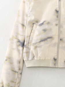 Detail of a tie-dye bomber jacket showing the zipper closure and ribbed hem texture