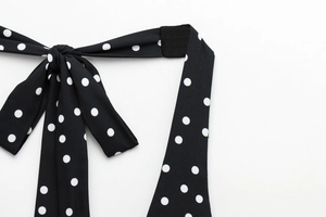 Detail of black polka dot halter top showing fabric texture and tied bow fastening
