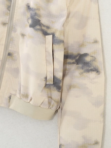 Macro detail of ripstop fabric and tie-dye pattern on woman's bomber jacket