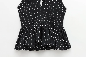 Detailed view of the V-neck and ruffled peplum hem on this black and white polka dot top
