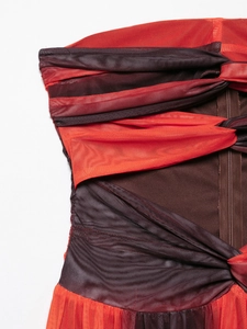 Detail of red mesh dress showing layered pleats, twist knot design, and side zipper