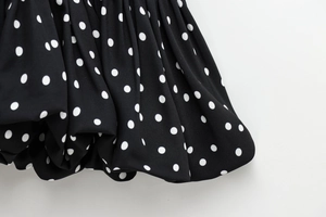 Close-up of black fabric with white polka dots showing soft texture and fluid drape
