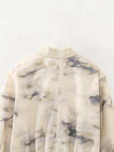 Detail of crewneck bomber jacket featuring artistic ink print and textured fabric