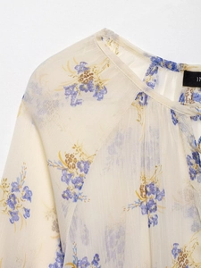 Detailed close-up of semi-transparent floral chiffon fabric and neck stitching details