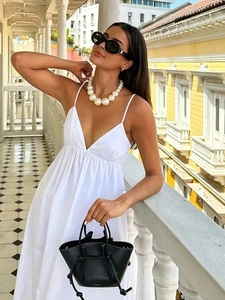 Detail of white V-neck backless maxi dress with spaghetti straps and pleated waist design