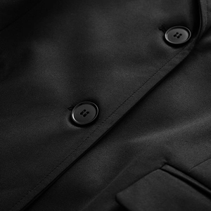Detailed close-up of double-breasted black knit blazer featuring premium twill fabric and buttons