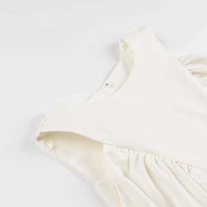 Detailed view of cream-colored tank top featuring pleated shoulder design and round neck