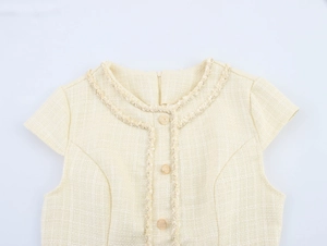 Détail de la robe en tweed beige avec col rond à franges et boutons dorés rétro