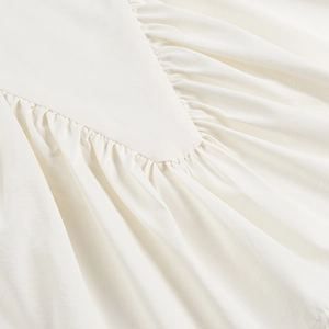 Close-up of white ruched fabric texture and gathered design on the women's tank top