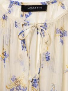 Detail of floral chiffon blouse neckline with round collar tie and pleated fabric texture