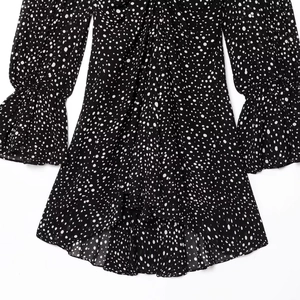 Elegant black long-sleeve polka dot mini dress with ruffled cuffs and tiered skirt layers