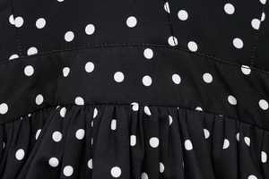 Macro shot of black polka dot fabric showing detailed stitching and gathered pleats