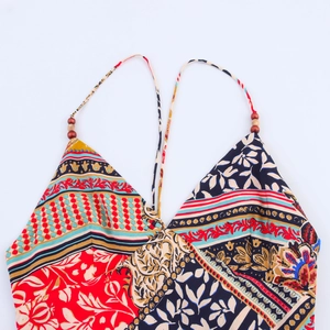 Detail of bohemian patchwork dress with halter neck ties and decorative wooden beads